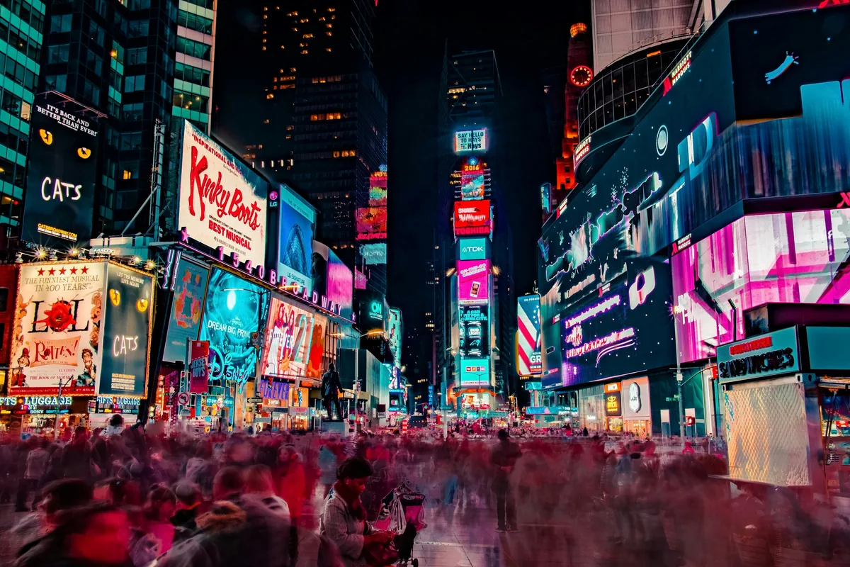 Times Square at night, ablaze with illuminated billboards and crowds.