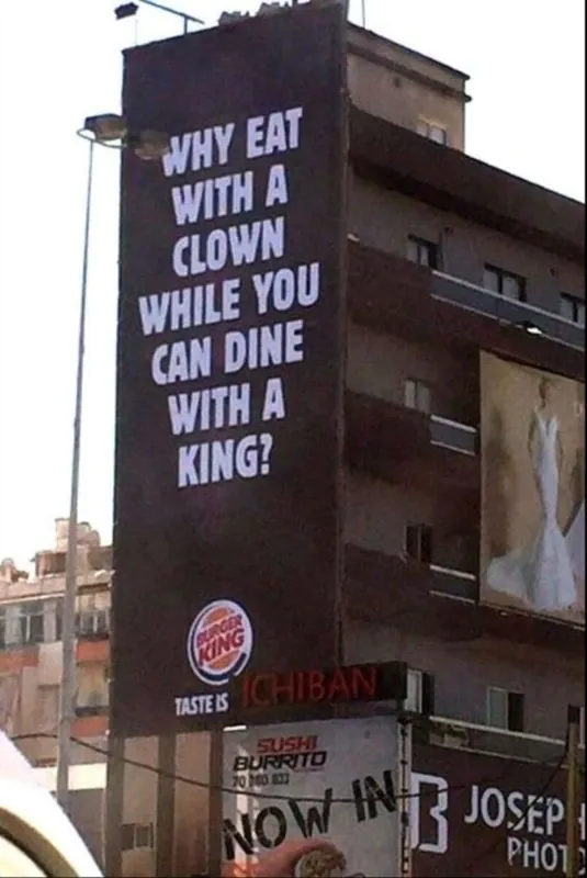Burger King billboard wrapped down the side of a building reading 'Why eat with a clown while you can dine with a king?'