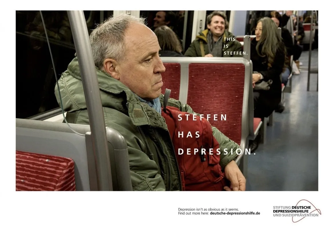 Awareness ad: a glum middle-aged man sits alone on a train while the passengers around him chat and smile. Text reads 'This is Steffen. Steffen has depression. Depression isn't as obvious as it seems.'